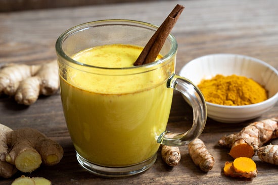 Die goldene Milch kommt aus der ayurvedischen Küche und erfreut sich auch hierzulande immer größerer Beliebtheit. Ein Glas goldene Milch, verfeinert mit einer Zimststange
